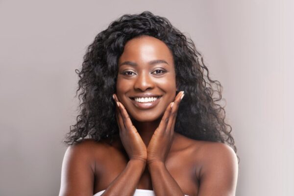 African American woman touching her smooth, glowing skin after Howganics PRP beauty treatment