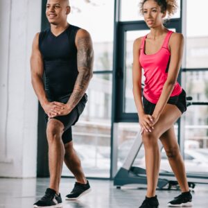 smiling african american couple of athletes doing exercise at gym