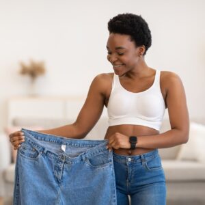 Black Lady Holding Jeans Too Big After Weight-Loss At Home