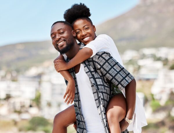 Portrait, black couple and back ride with a smile in nature outdoors on a date, trip or vacation. L