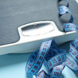 Scales and measuring tape on a blue background representing weight loss and fat metabolism benefits of Howganics L-Carnitine Shot
